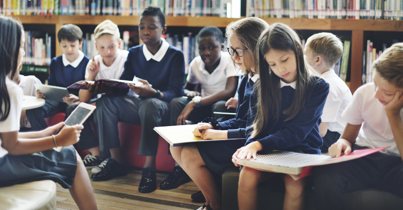 A classroom of students sitting together in the library reading. 